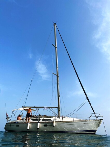 A sailboat with a tall mast and rigging, anchored in calm waters under a clear sky. 3
