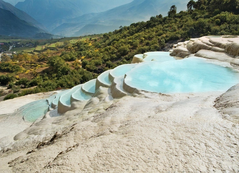 Terraced pools of clear water, a mountainous landscape, and dense greenery. 1