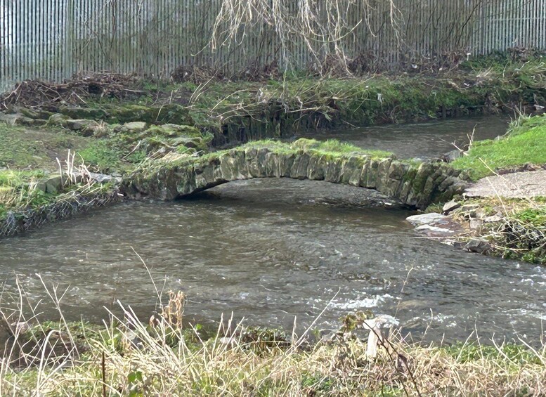 A small stone bridge over a flowing stream in a natural setting. 2