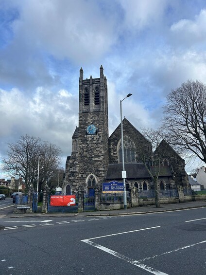 A historic church with a clock tower, a blue signboard, and a red banner. 3