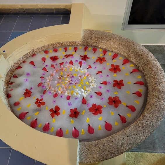 A decorative water feature with a stone basin, surrounded by colorful flower petals. 4