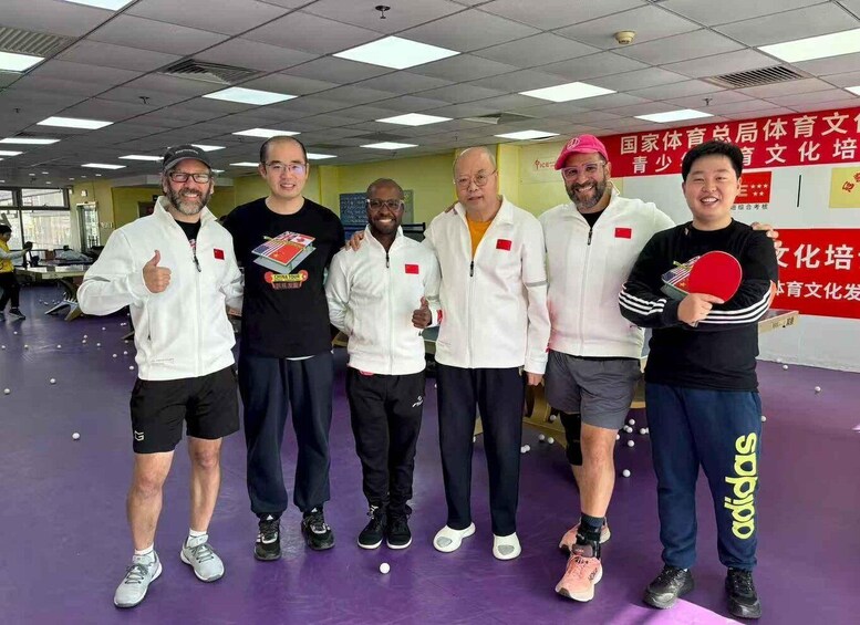 A group of people in a sports hall with a badminton racket and shuttlecocks on the floor. 1