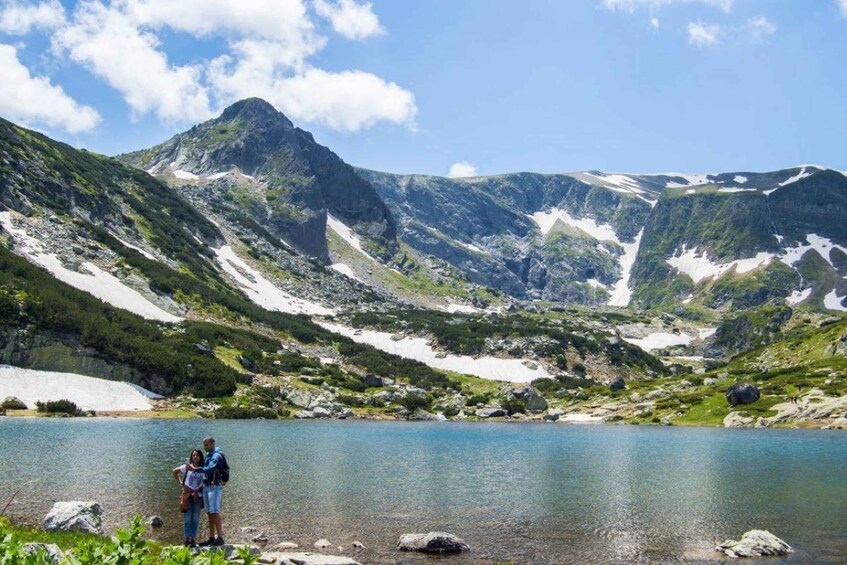 A mountainous landscape with a lake, rocky terrain, and a person standing by the water. 3