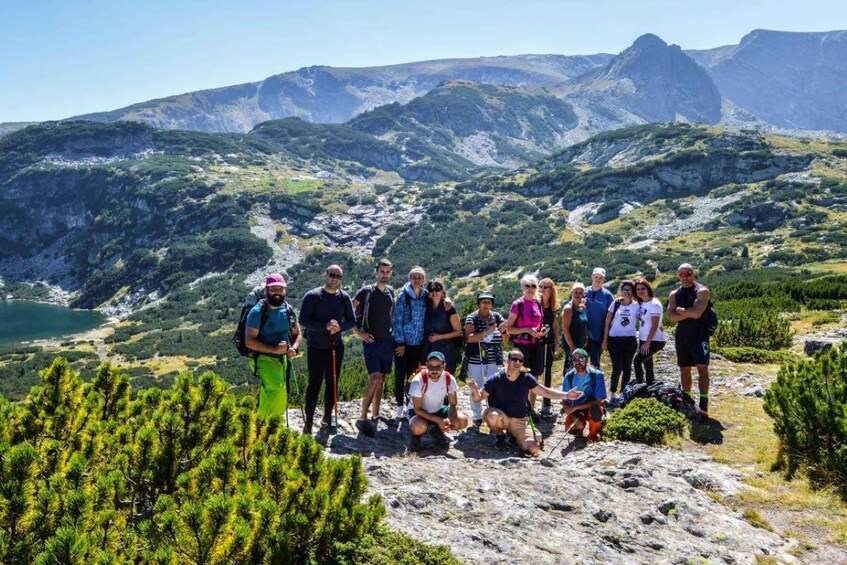 A group of hikers on a mountainous trail with a lake and rocky terrain in the background. 5