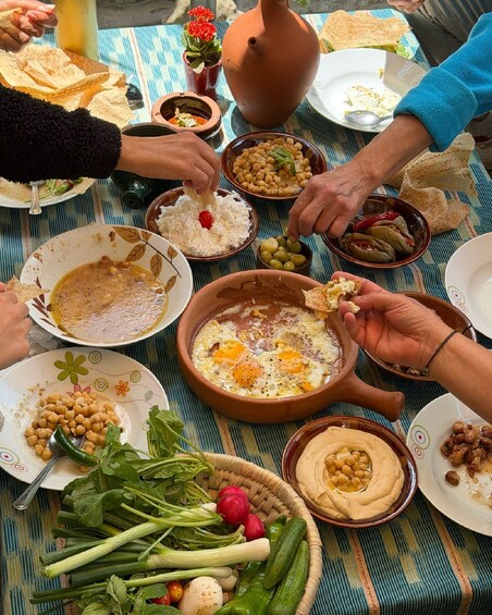 A communal meal with various dishes, including chickpeas, eggs, and bread, on a striped tablecloth. 5