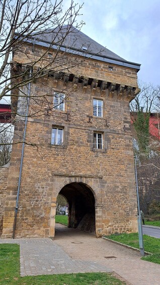 A stone building with a central archway, surrounded by grass and a paved walkway. 4