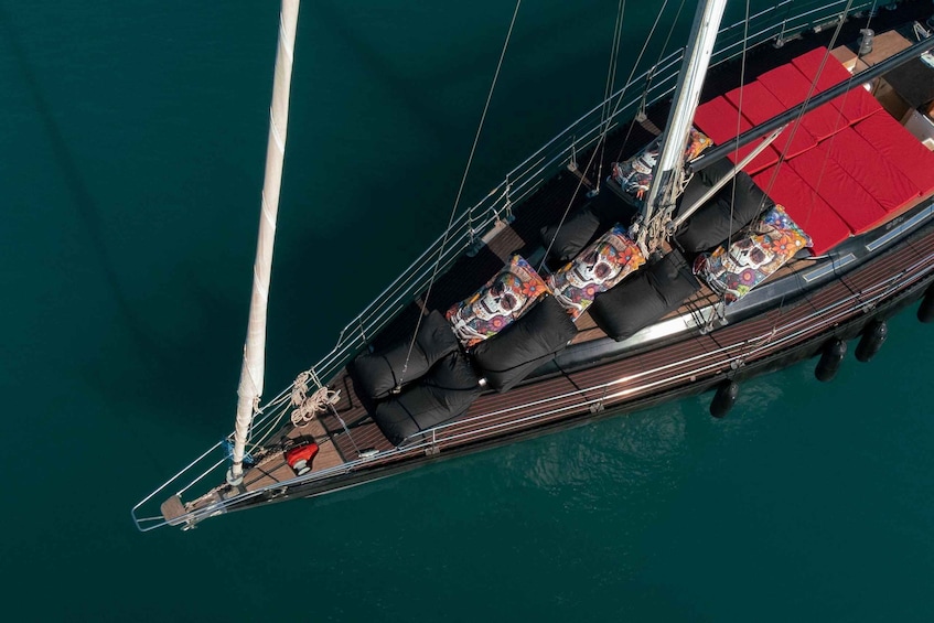 A sailboat with multiple deck chairs and a red awning. 1