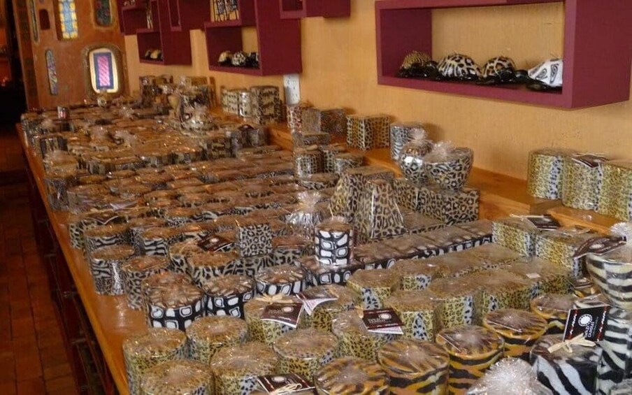 A display of various patterned boxes and containers, likely for sale, in a store with wooden flooring and red shelving units. 3