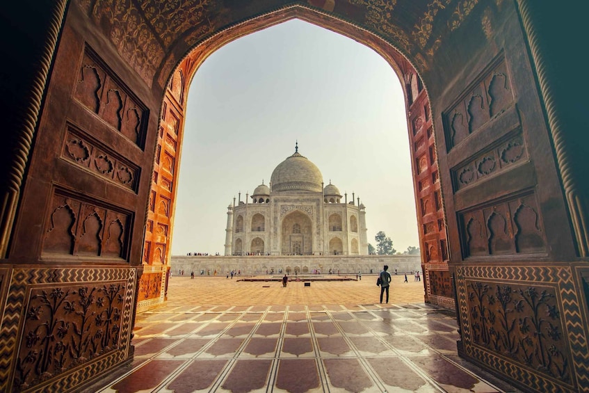 The Taj Mahal with intricate carvings on the archway and a clear view of the monument. 1