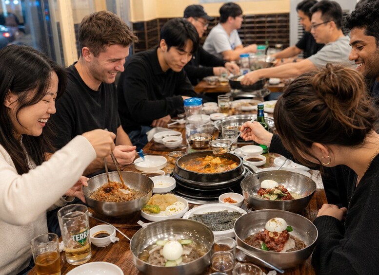 A group of people dining at a restaurant with various dishes and drinks on the table. 4