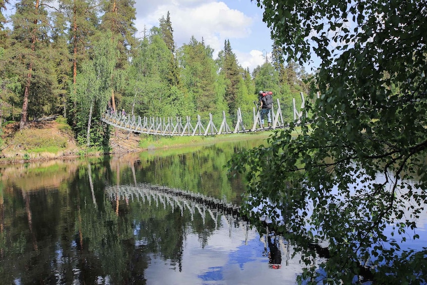 A wooden bridge over a calm lake surrounded by dense forest. 2