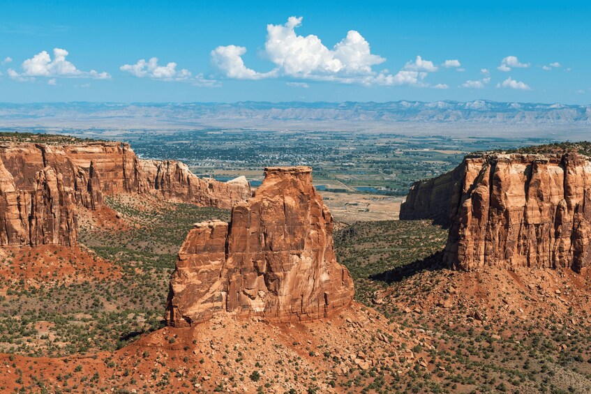 A canyon landscape with prominent rock formations and a distant city view. 2