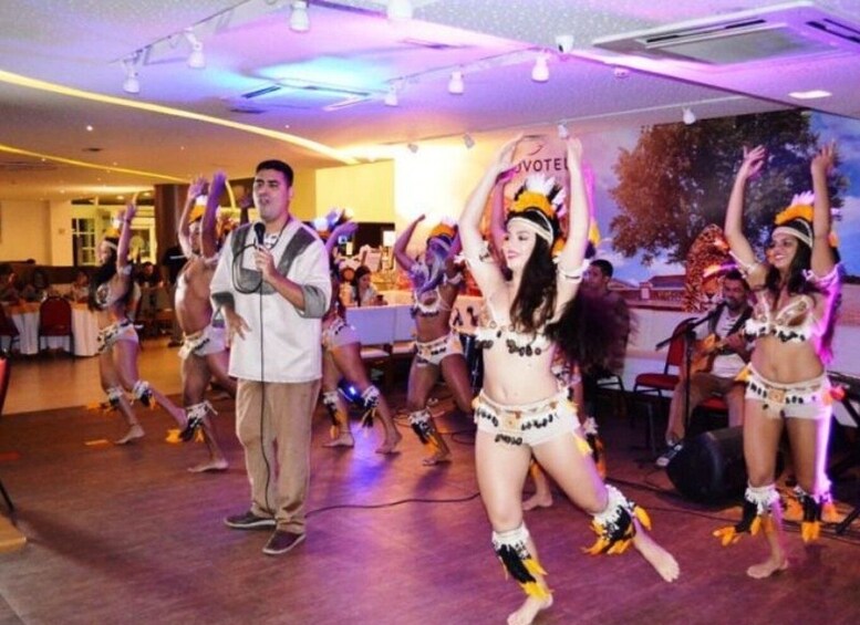 A group performing a dance routine in a well-lit indoor venue with a stage and audience seating. 5