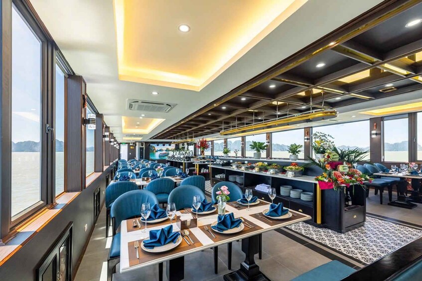 A restaurant with blue upholstered chairs, white tablecloths, and a view of the sea. 3