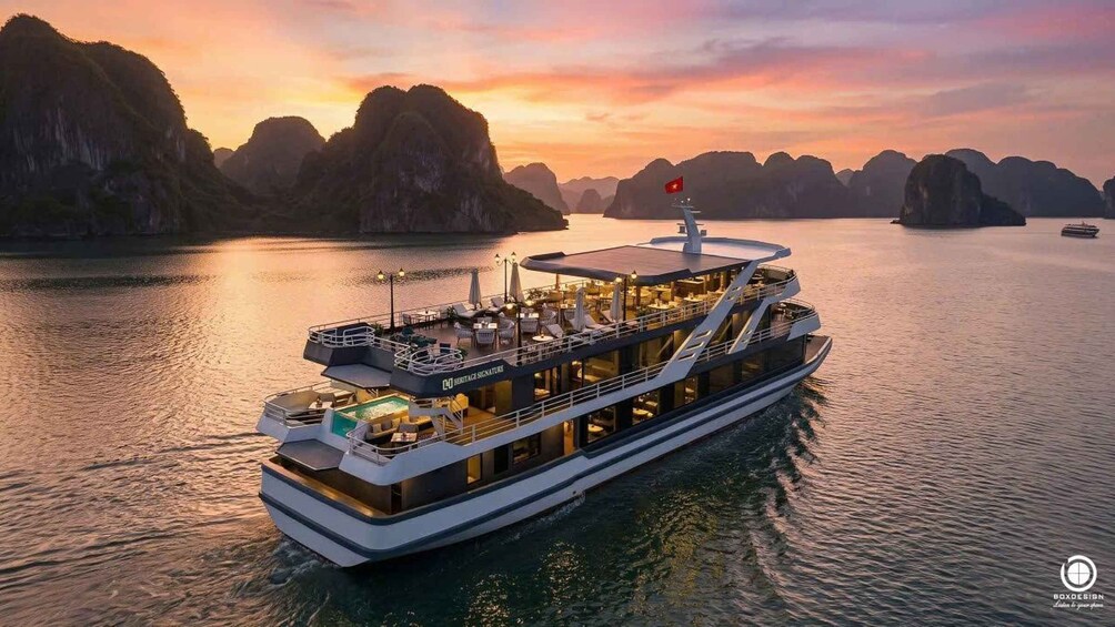 A large river cruise ship with a dining area and a flag on top, surrounded by mountainous landscape during sunset. 1