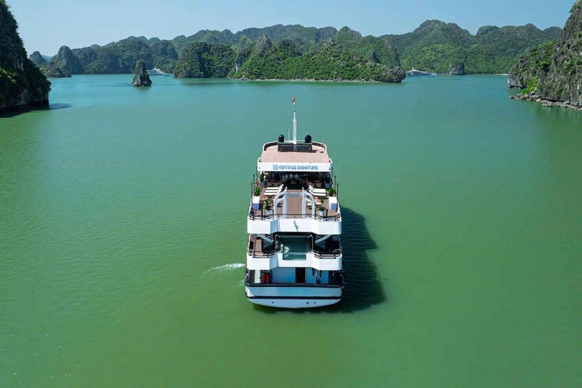 A white boat with 'Heritage Signature' on the front, moving through a greenish river surrounded by forested hills. 5