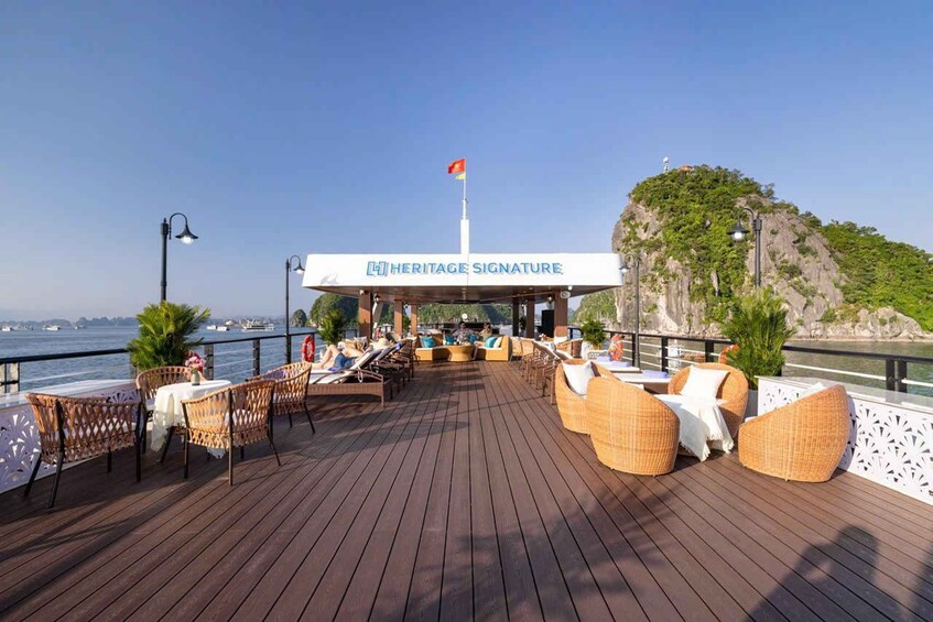 A deck with wicker furniture, a sign reading 'Heritage Signature,' and a flag on a hill in the background. 4