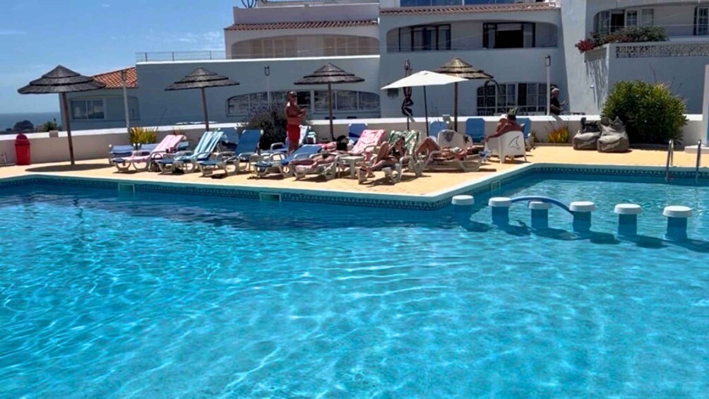 A clear blue pool with lounge chairs and umbrellas. 5