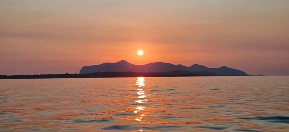 A sunset over a calm body of water with mountains in the background. 3