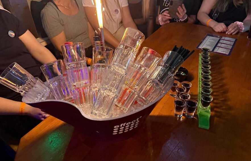 A bar with a unique drink dispenser filled with shot glasses. 3