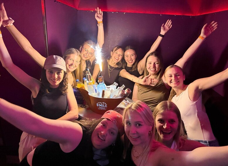 A group of people with their arms raised, a bucket of 9 Mile Vodka, and sparklers. 1