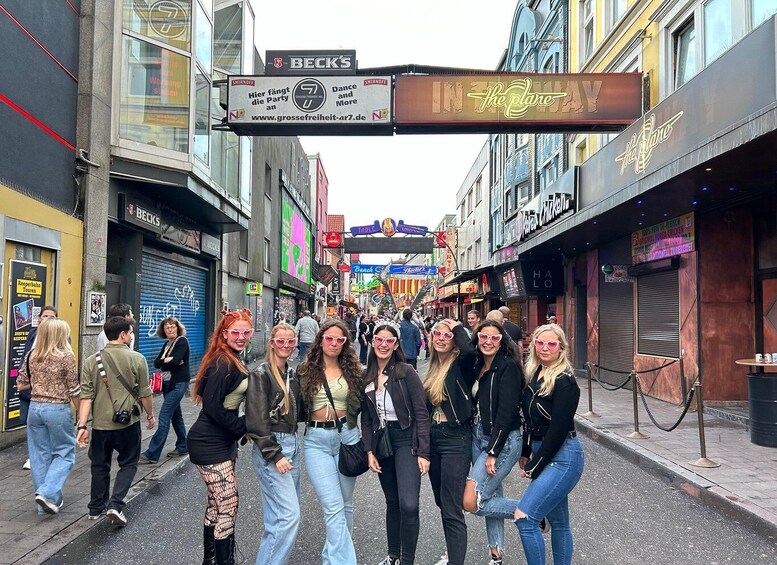 A group of people walking on a street lined with shops and signs, including a Beck's sign and a sign for 'In the Plane.' 4