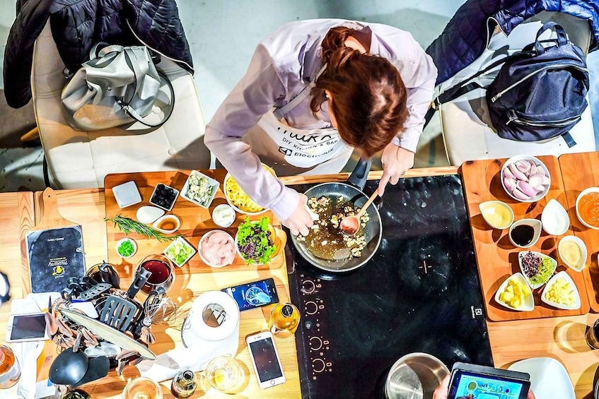 A person cooking on a portable stove with various ingredients and utensils on a wooden table. 3