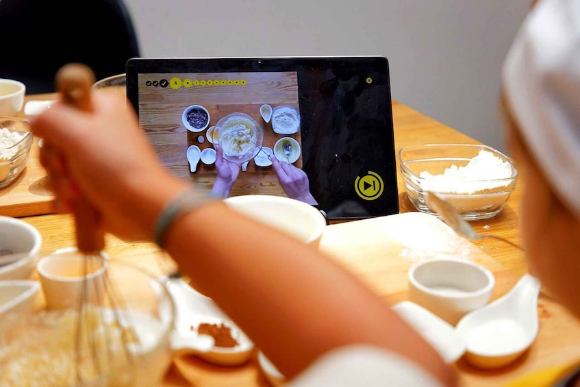 A person using a tablet to follow a recipe while preparing food. 1