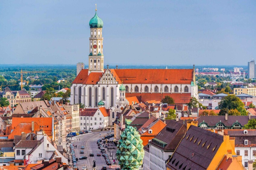 A cathedral with a clock tower, surrounded by historic buildings and a busy street. 1