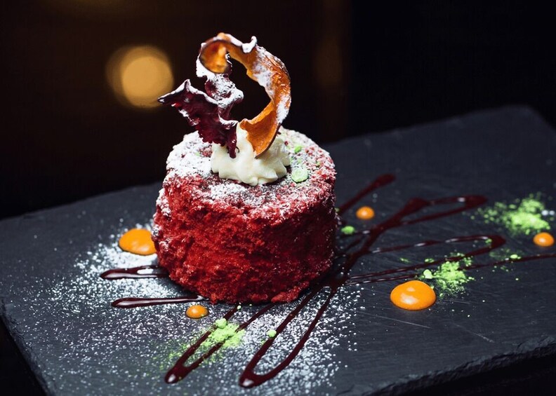 A dessert on a slate plate with powdered sugar, chocolate drizzle, and a decorative leaf. 2