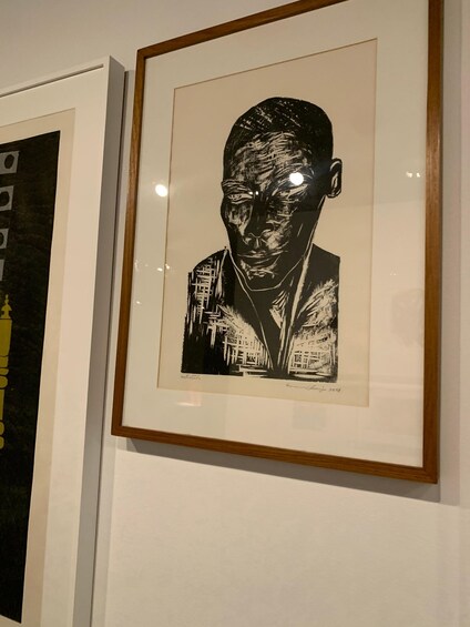 A framed black and white artwork with a signature at the bottom right. 4