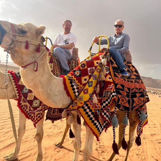 Two camels with riders in a desert landscape. 5