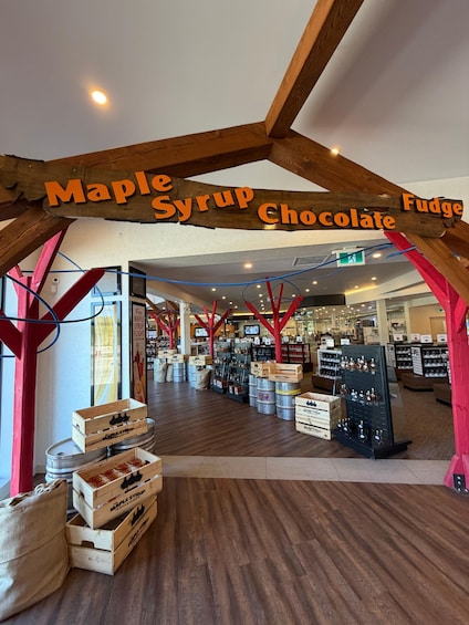 A maple syrup and fudge shop interior with wooden beams, wooden crates, and shelves of products. 5