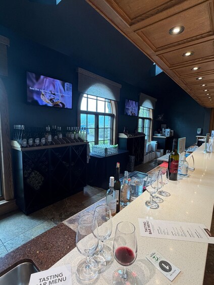 A tasting bar with wine bottles and glasses on display. 1