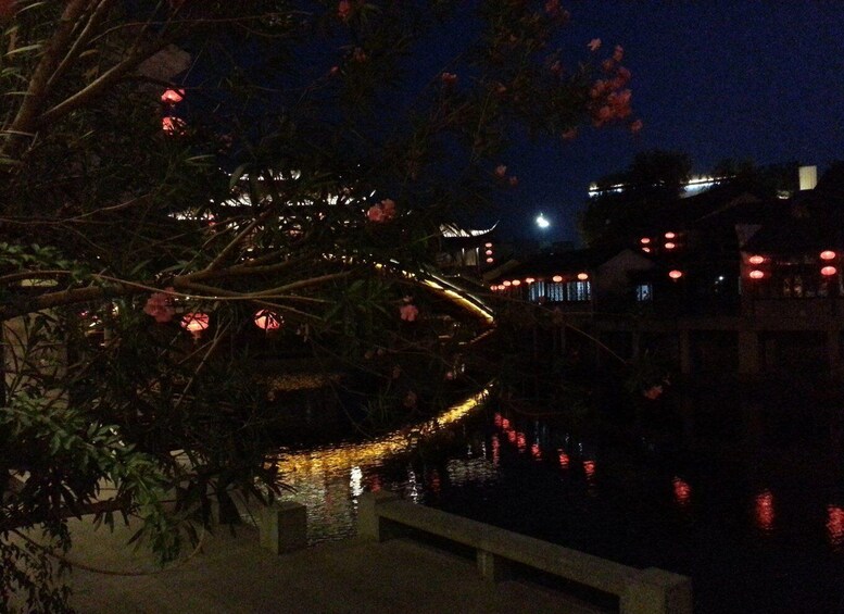 A night scene with a river reflecting lights, a bridge, and buildings with red lanterns. 5