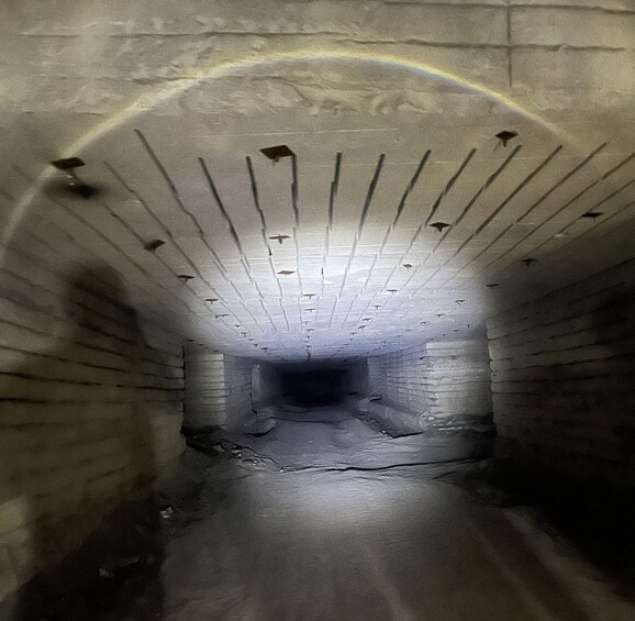 A tunnel with a patterned ceiling and brick walls. 2