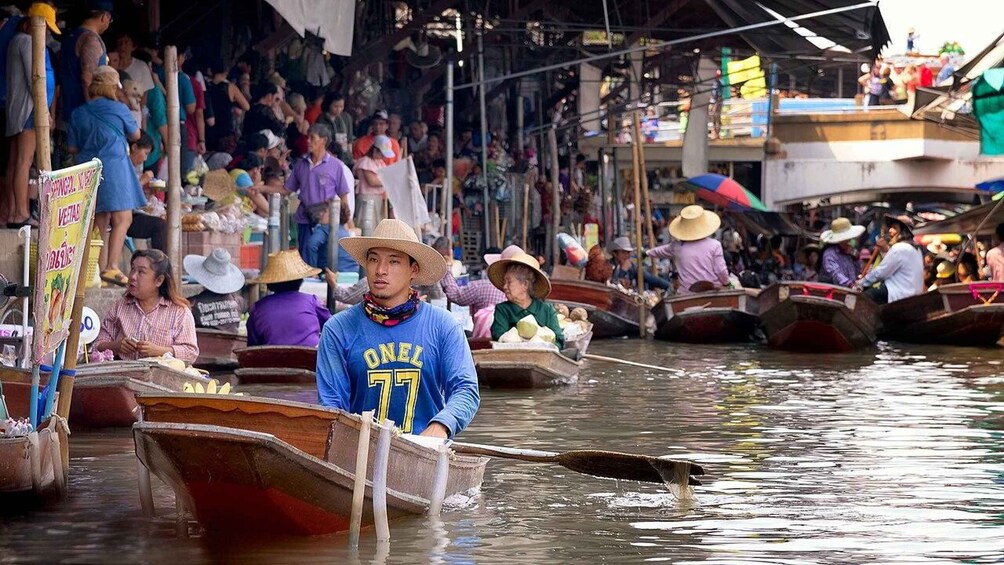 A crowded waterway with people in boats, some wearing hats, and a person in a blue shirt with the number 77. 5