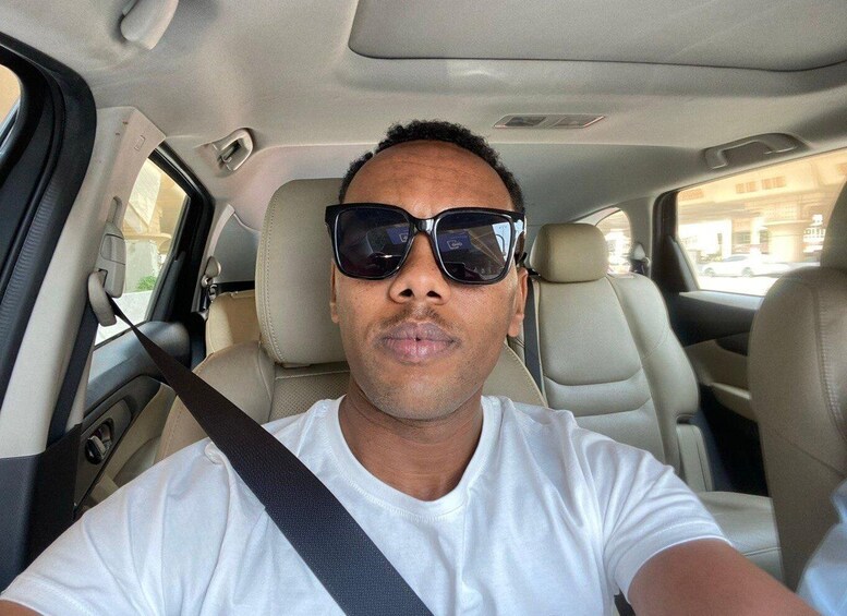 A person seated in a car with beige leather seats and a seatbelt. 4