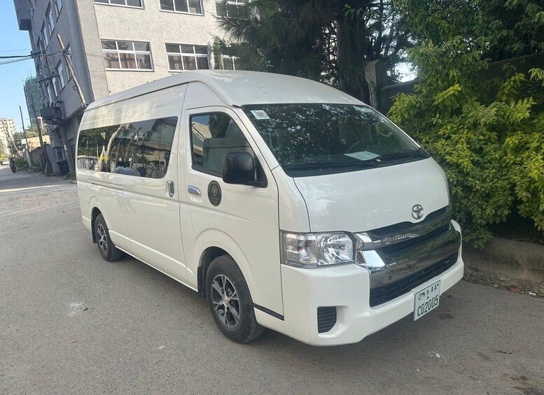 A white van parked on a street with buildings and trees in the background. 5
