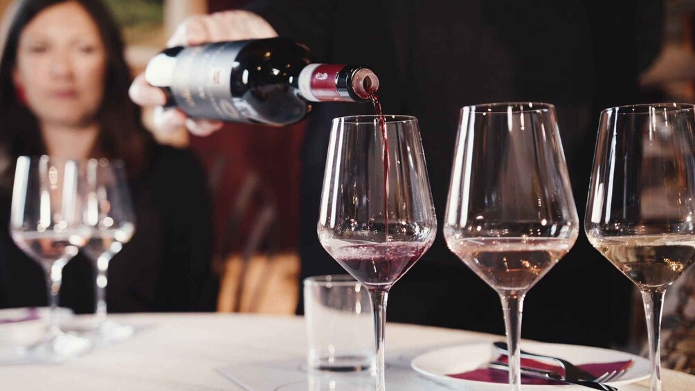 A person pouring wine into glasses on a table. 5