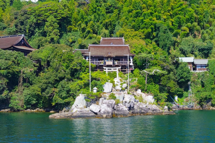 A traditional Japanese building on a rocky island surrounded by lush greenery and water. 2