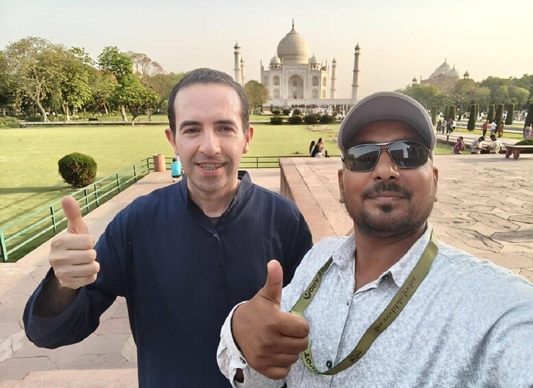 Two people giving thumbs up in front of the Taj Mahal. 4