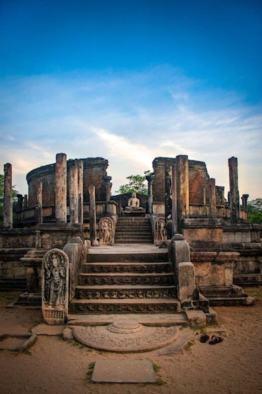 Ancient stone ruins with a central staircase leading to a seated figure. 1