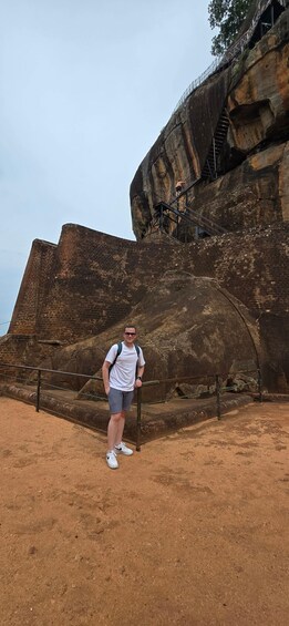 A person standing in front of a large rock formation with a staircase leading up. 3