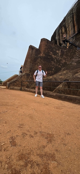 A person standing in front of a large brick structure with a staircase leading up to it. 2
