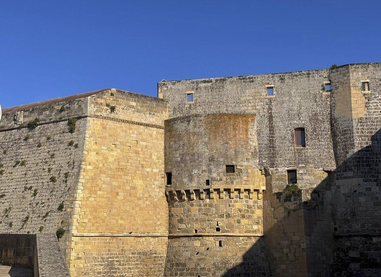 A historic stone wall with battlements and small windows. 1