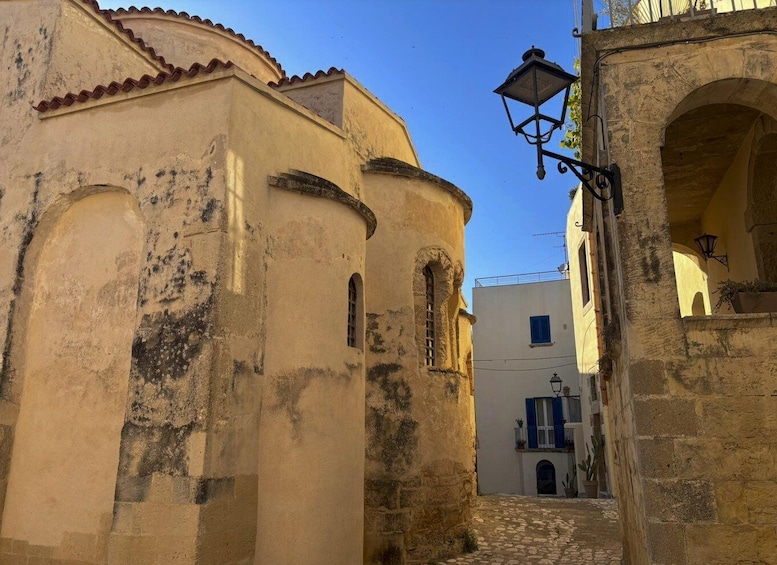 A narrow cobblestone street flanked by historic buildings with arched windows and a street lamp. 4