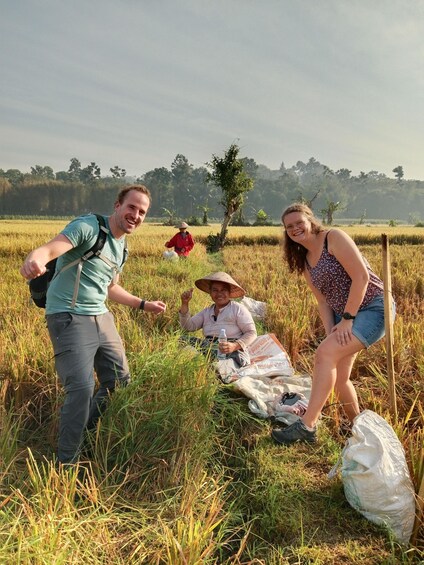 Three people in a field with a woman sitting on a blanket, a man standing, and another person in red. 4