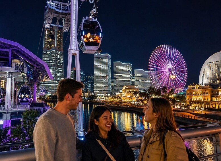 A cityscape at night with illuminated buildings, a Ferris wheel, and a cable car system. 1