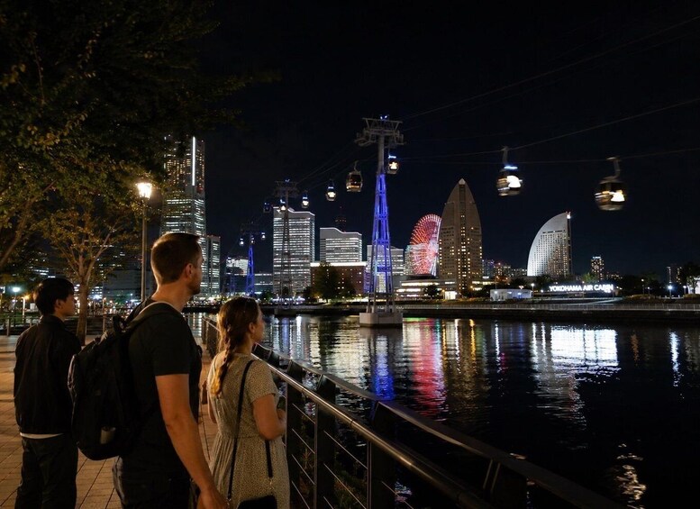 A nighttime cityscape with illuminated buildings, a river, and a Ferris wheel. 3